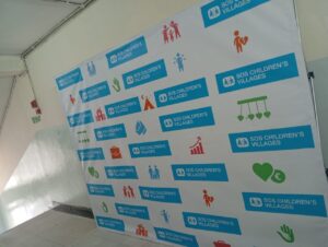Wall banner with repeated logos and colorful icons representing family, care, and community.
