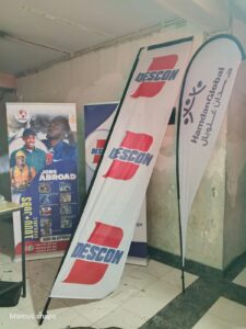 Indoor promotional banners for DESCON and Hamdan Global, alongside a “Jobs Abroad” banner with contact numbers.