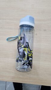 Transparent bottle with comic-style Batman panels in black, gray, yellow, and white.