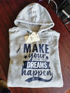 Gray hoodie with bold black and white text reading ‘Make your dreams happen,’ branded with King’s Collection tag.