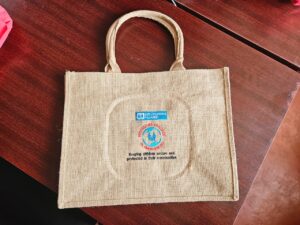 Eco‑friendly beige jute tote bag printed with SOS Children’s Villages logo and Protecting Children in Emergencies emblem, promoting child protection and community safety branding.