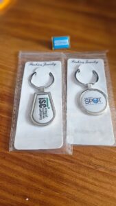 Metallic teardrop keychain branded “ISC Integral Supplies Company” and a circular metallic keychain branded “THE DIRTY SPOT CLEANING SERVICES” packaged in clear sleeve on Fashion Jewelry card.