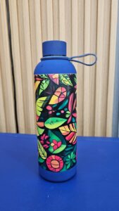 Blue water bottle decorated with multicolored floral and leaf patterns, featuring vibrant artistic design and loop‑handle cap, promotional custom drinkware for branding.