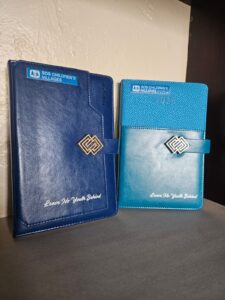 Blue leather planners embossed with SOS Children’s Villages logo and slogan ‘Leave No Youth Behind,’ custom organizational diaries for 2025.