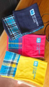 Plaid scarves in navy, red, and yellow embroidered with SOS Children’s Villages logo, branded textile merchandise.